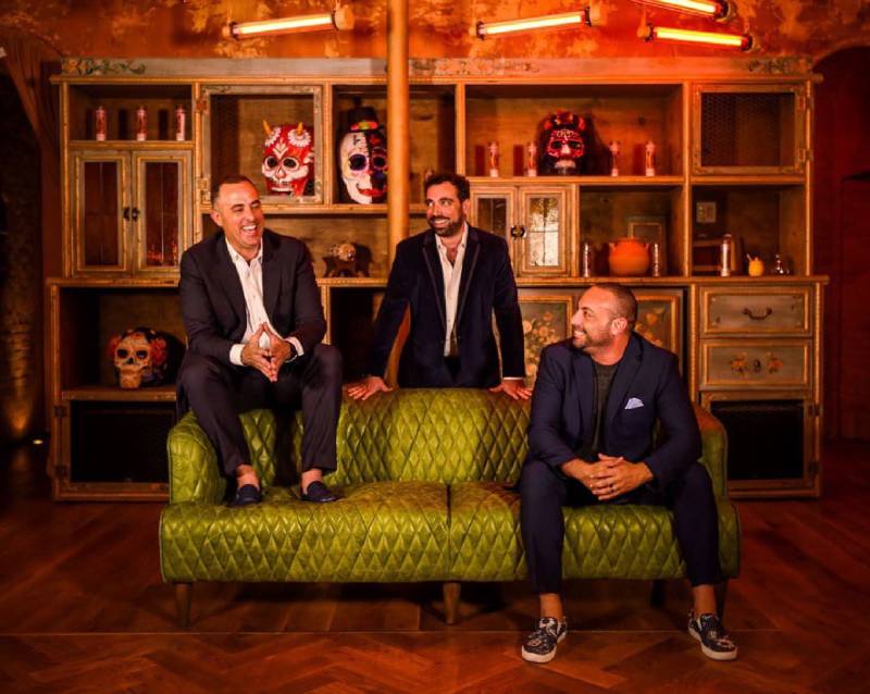 three men dressed in suits sitting on a couch